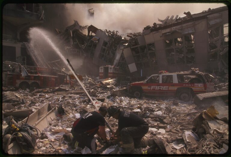 Two rescue workers direct a firehose at the ruins of the World Trade Center following the 9/11 terrorist attacks